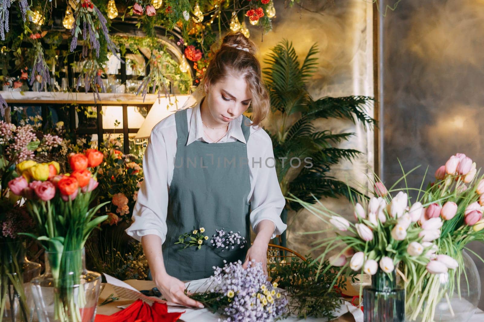 A woman in her florist shop collects bouquets of flowers. The concept of a small business. Bouquets of tulips for the holiday on March 8