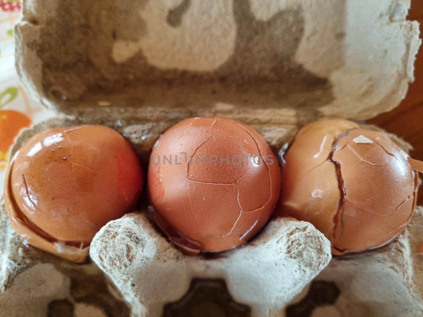Three brown eggs with cracks nestled in a paper egg carton