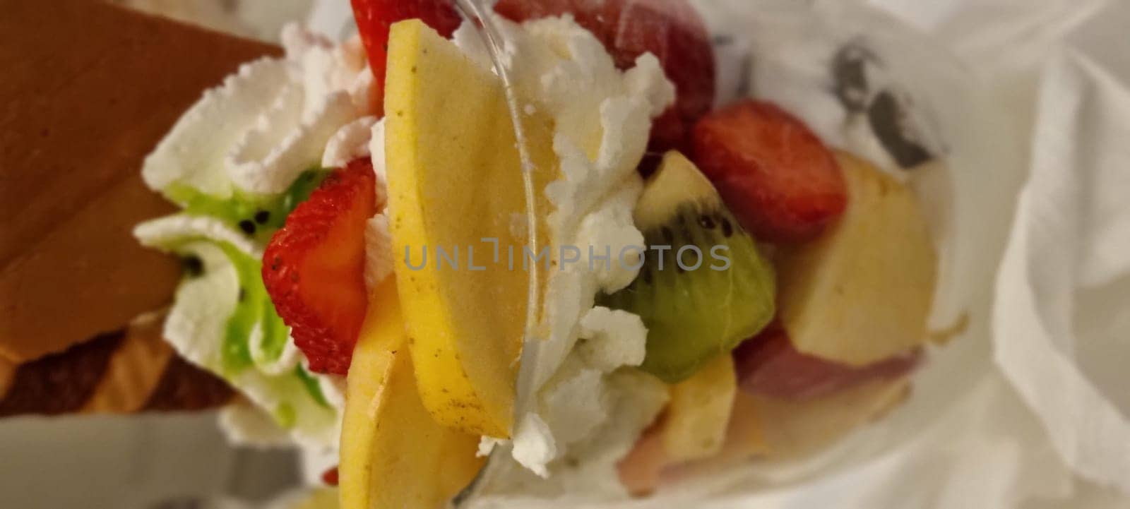 Close-up of a waffle cone overflowing with fresh fruit and scoops of rich ice cream