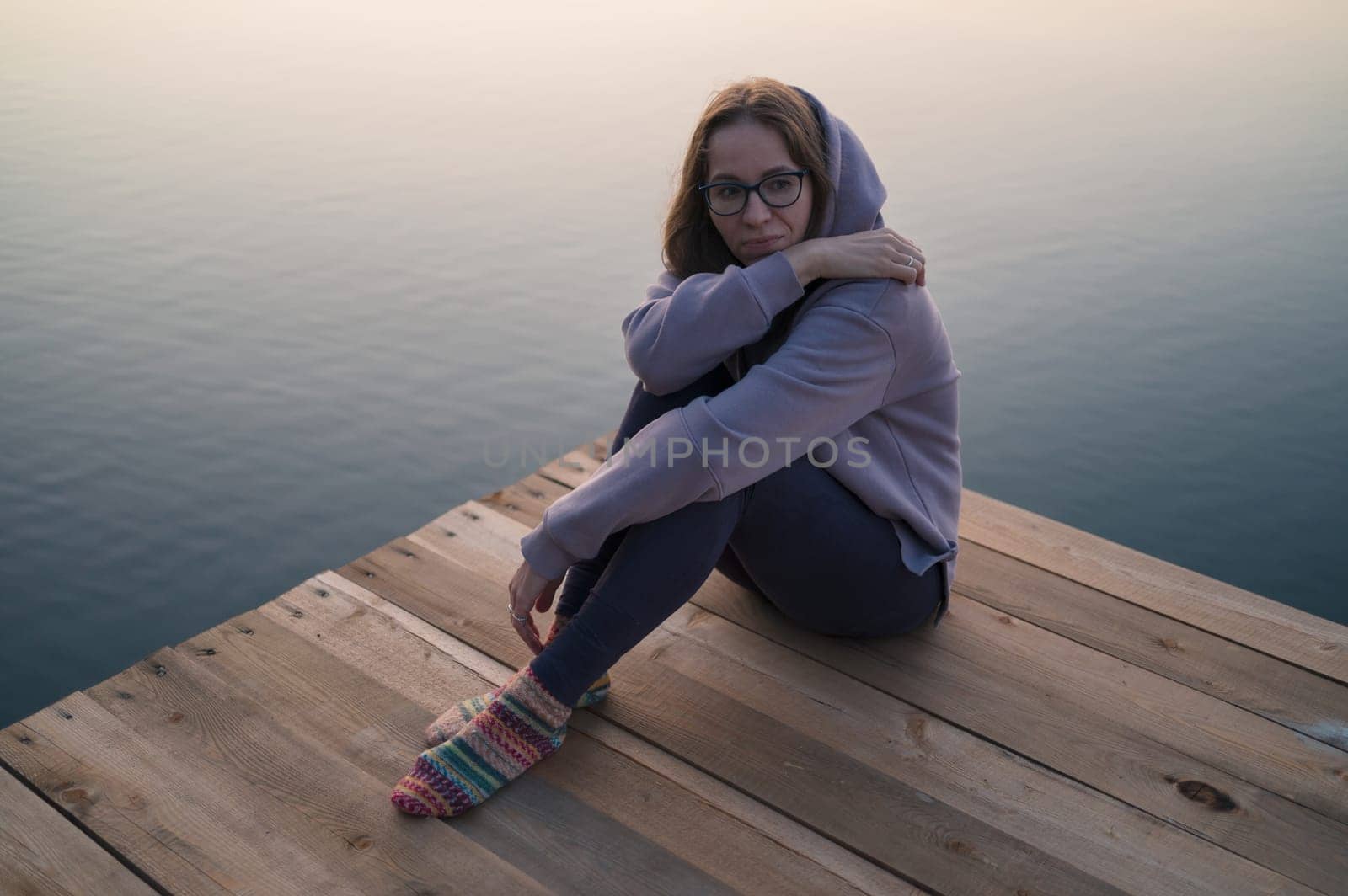 Woman sitting on the pier, closeup portrait, summer sunset