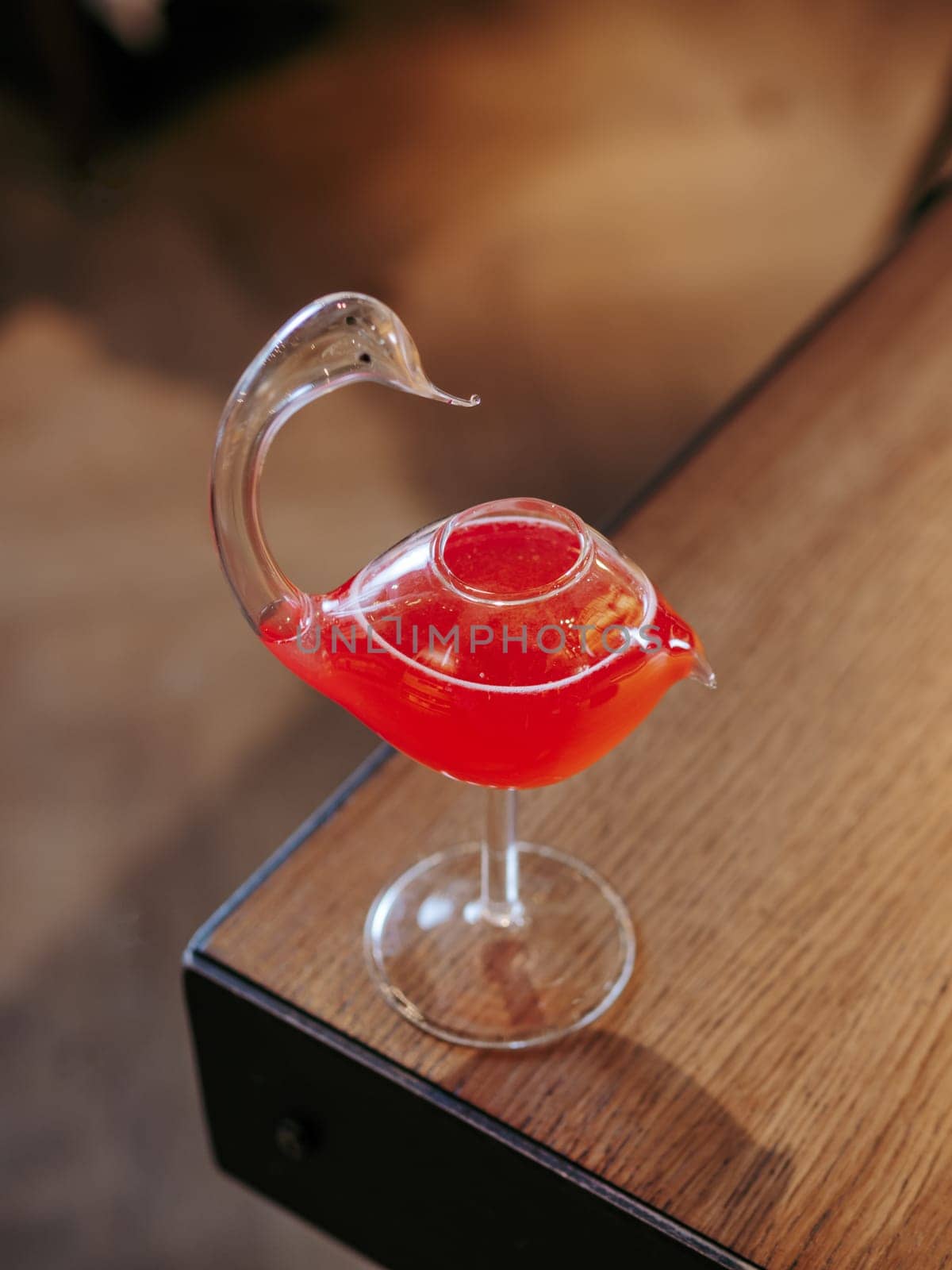 Cosmopolitan cocktail in swan bird glass, minimalistic aesthetic photo on bar counter edge. Popular alcoholic cosmopolitan cocktail made with vodka, triple sec, cranberry juice, lime juice. Bar menu