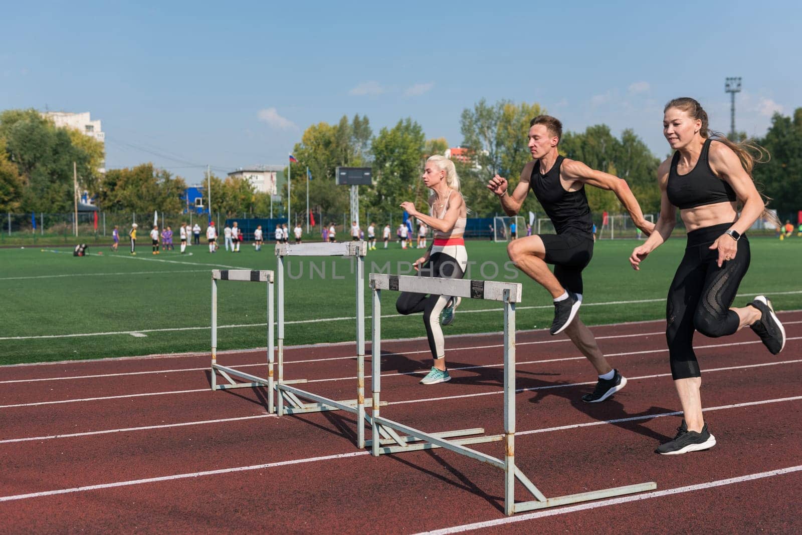 Two athlete woman and man runnner running hurdles at the stadium outdoors