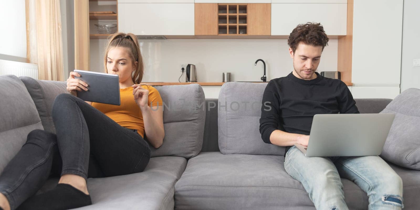 Crisis in a partnership, separation, internet addiction. Couple separated on sofa in living room
