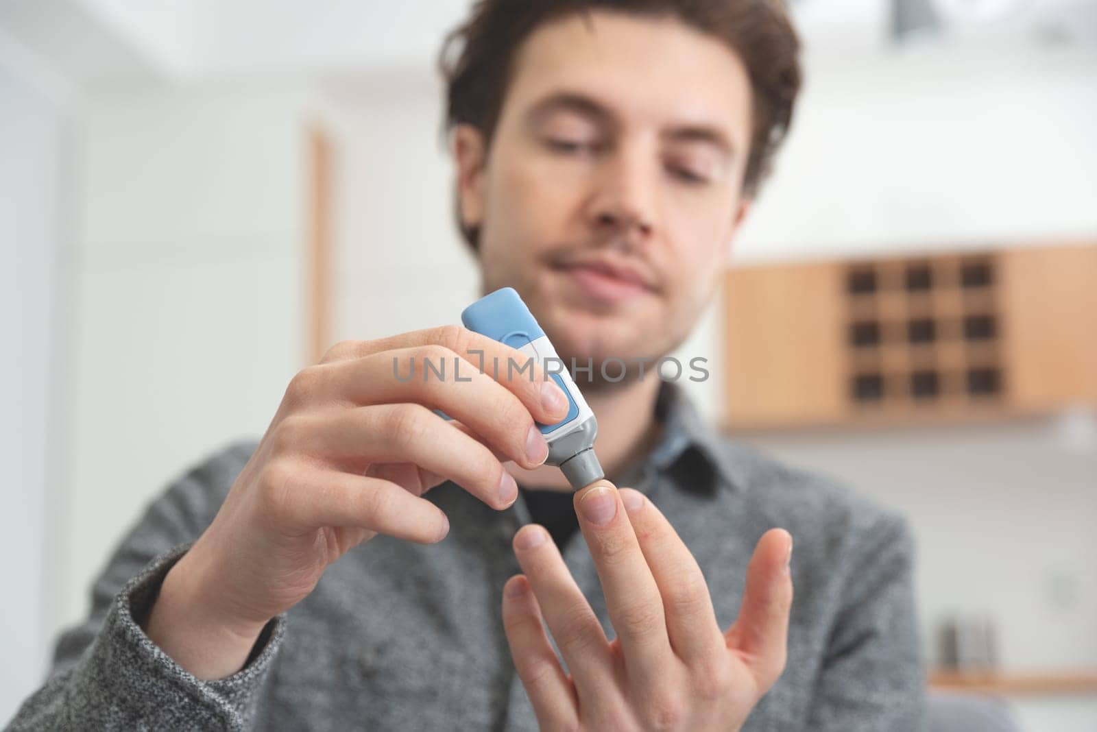 Young man measures blood sugar level. Diabetes using lancet.