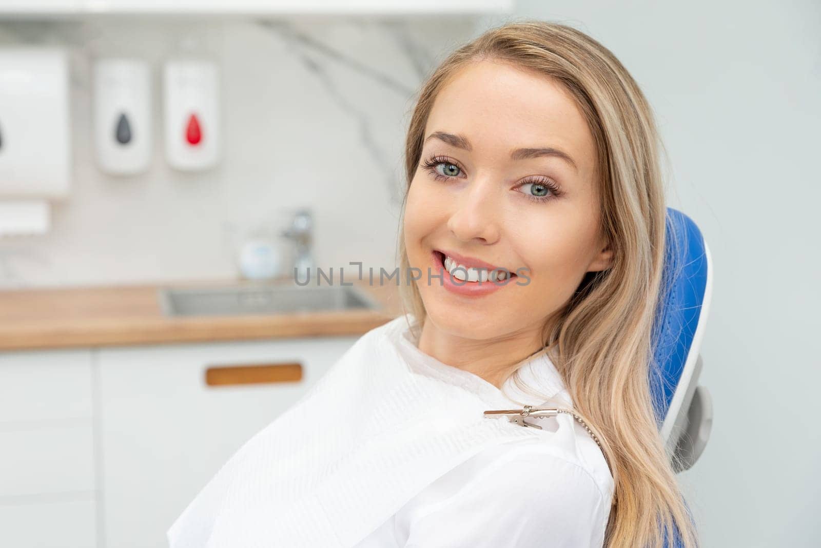 Young smiling woman sitting on chair at dentist office. Dental care, healthy teeth.