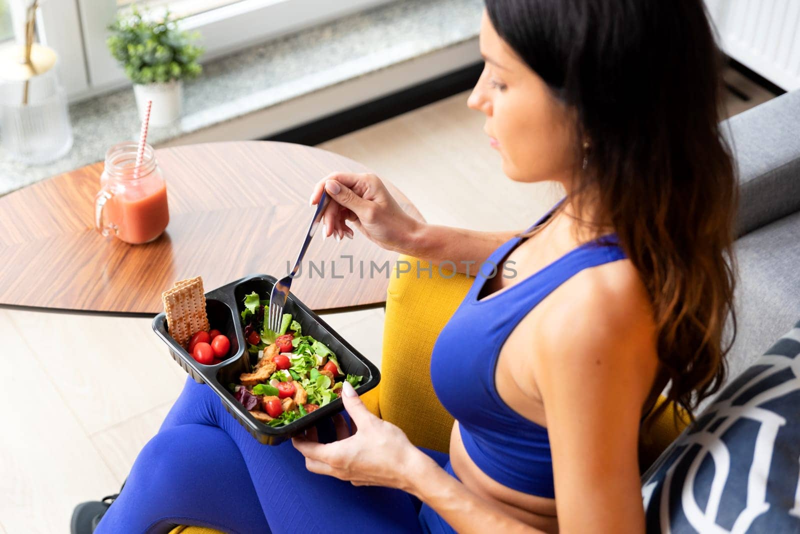 Fit woman eating healthy food at home. Healthy lifestyle concept with fitness catering