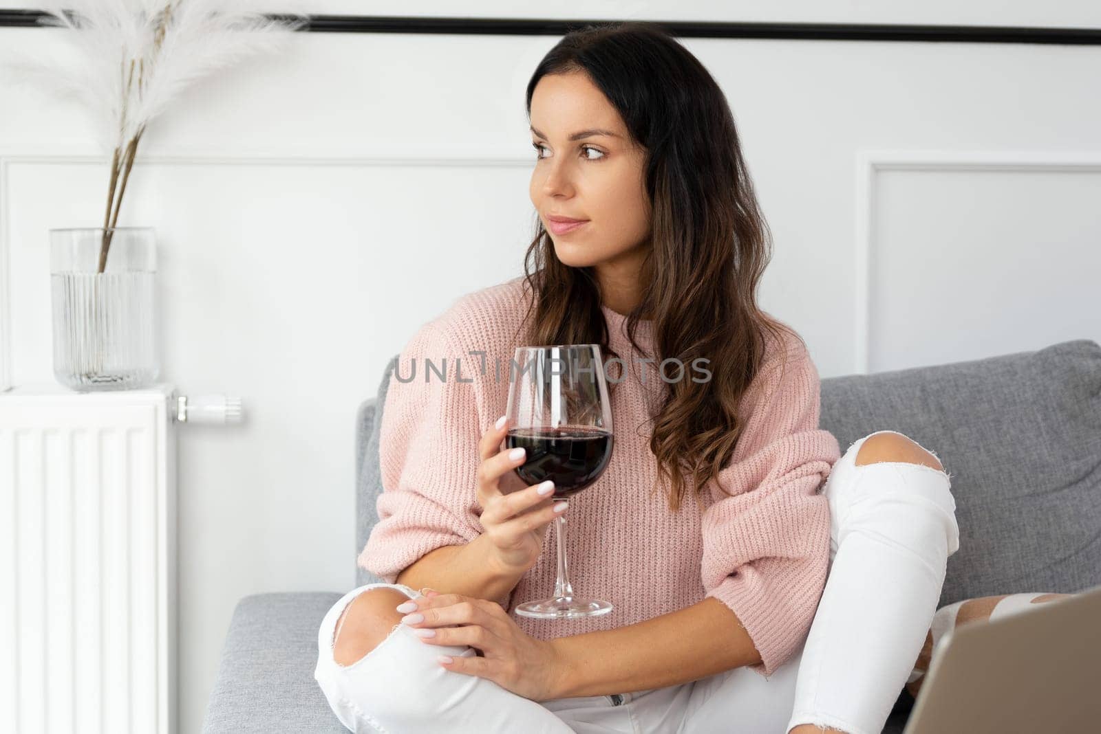 Woman sitting on couch, resting with glass of red wine