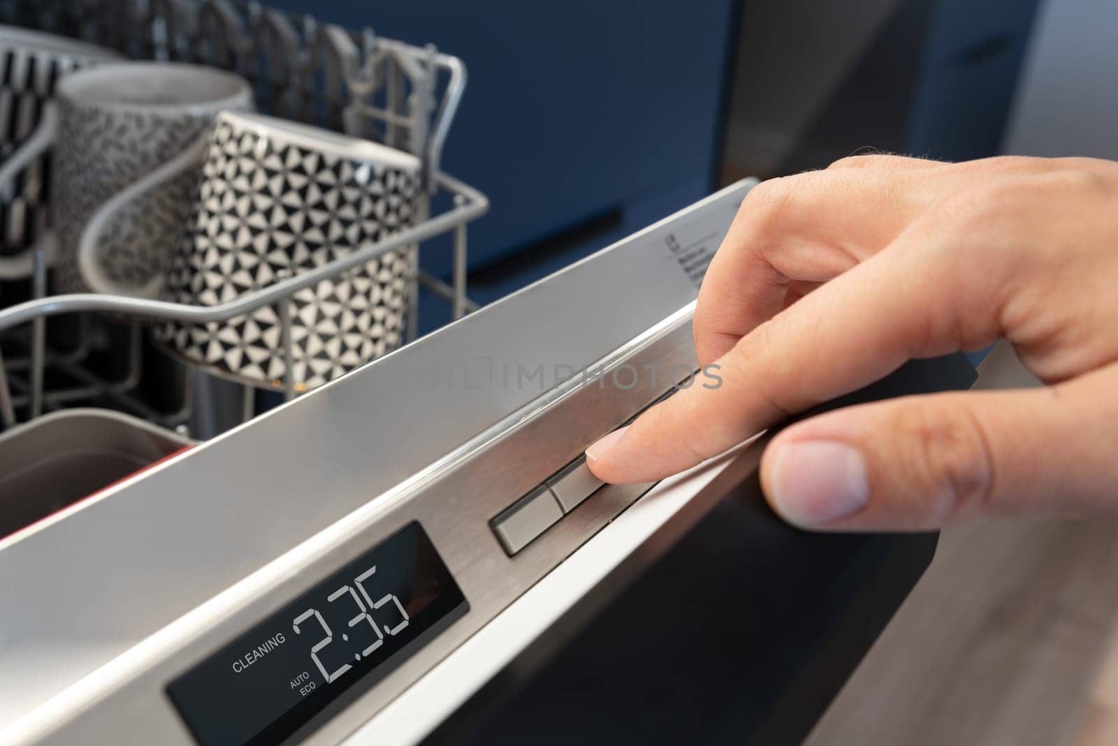 Man pushing start button on the control panel of the dishwasher.