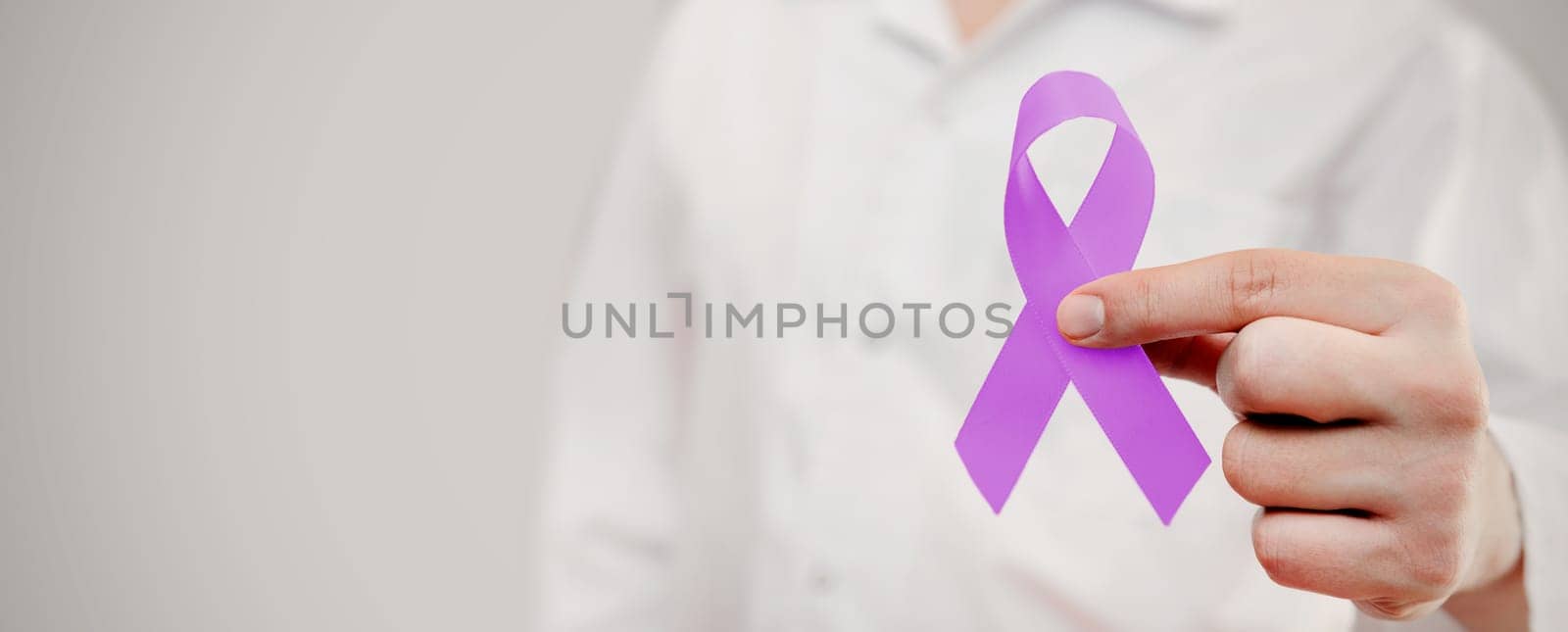 Man holding pancreatic cancer awareness ribbon. National cancer survivors month.