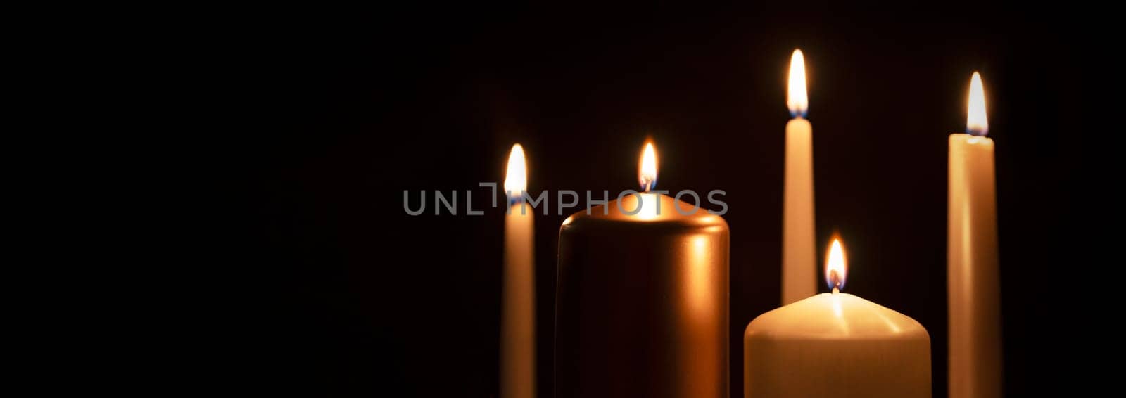 Funeral symbol with burning candle in darkness. Copy space.