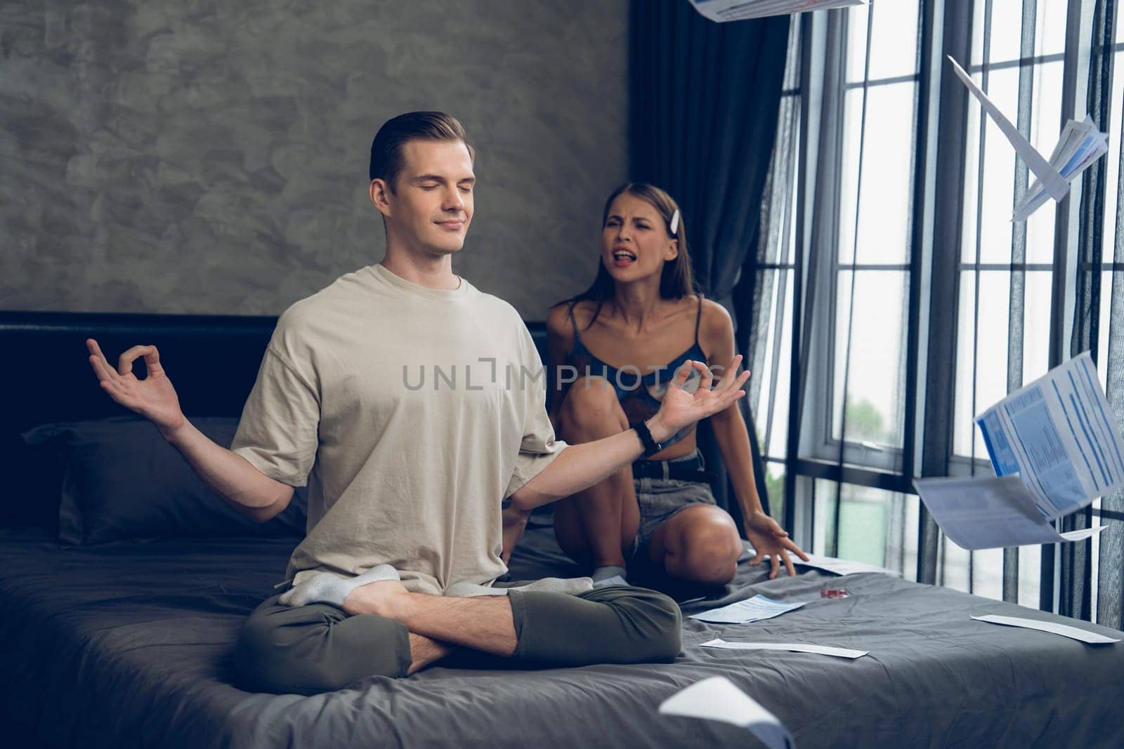 Young man doing mindfulness meditation ignoring his wife. Unveiling by biancoblue