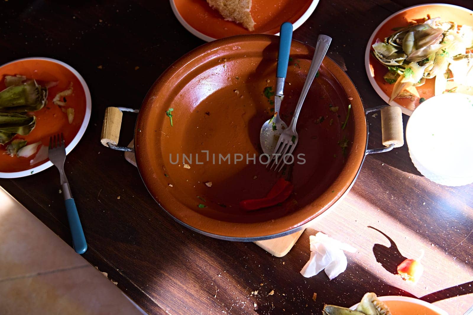 View from above of an empty dirty tagine and plates with the leftover of food after lunch or dinner. Food and drink consumerism