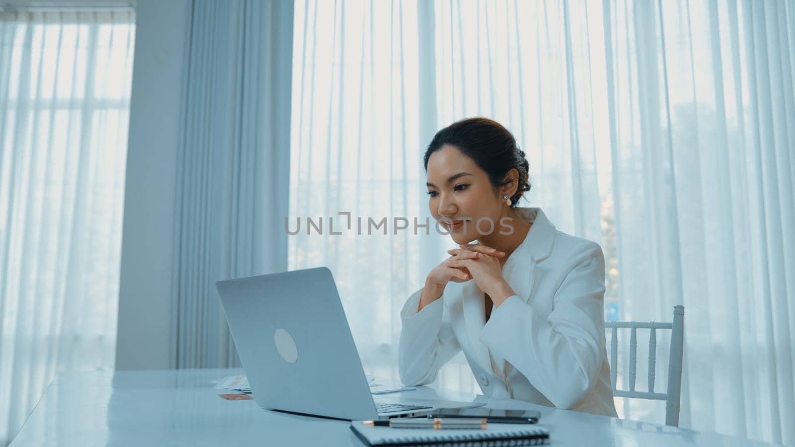 Young businesswoman sitting on the workspace desk using laptop computer for internet online content writing or secretary remote working from home. Vivancy