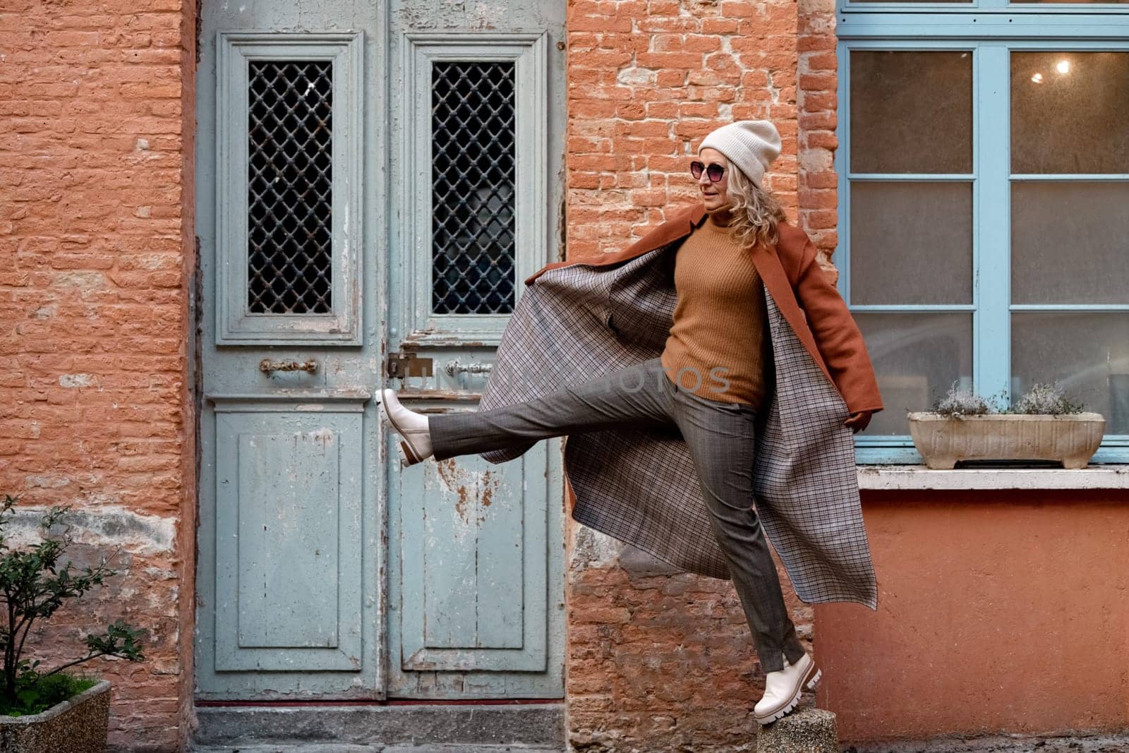 A woman in terracotta coat and leather gloves in the city by Godi