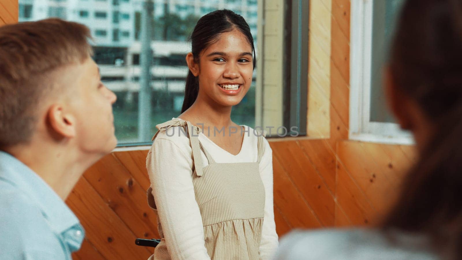 Young student smiling while listening other student in meeting or group discussion. Cute teenager talking about her experience and sharing to friends in mixed races. Creative education. Edification.