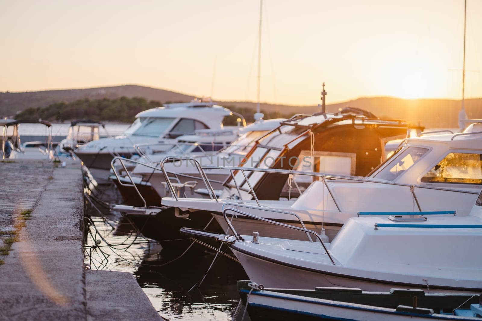 Motor boats in row at stone pier, sunset at port of Biograd na Moru port in Croatia