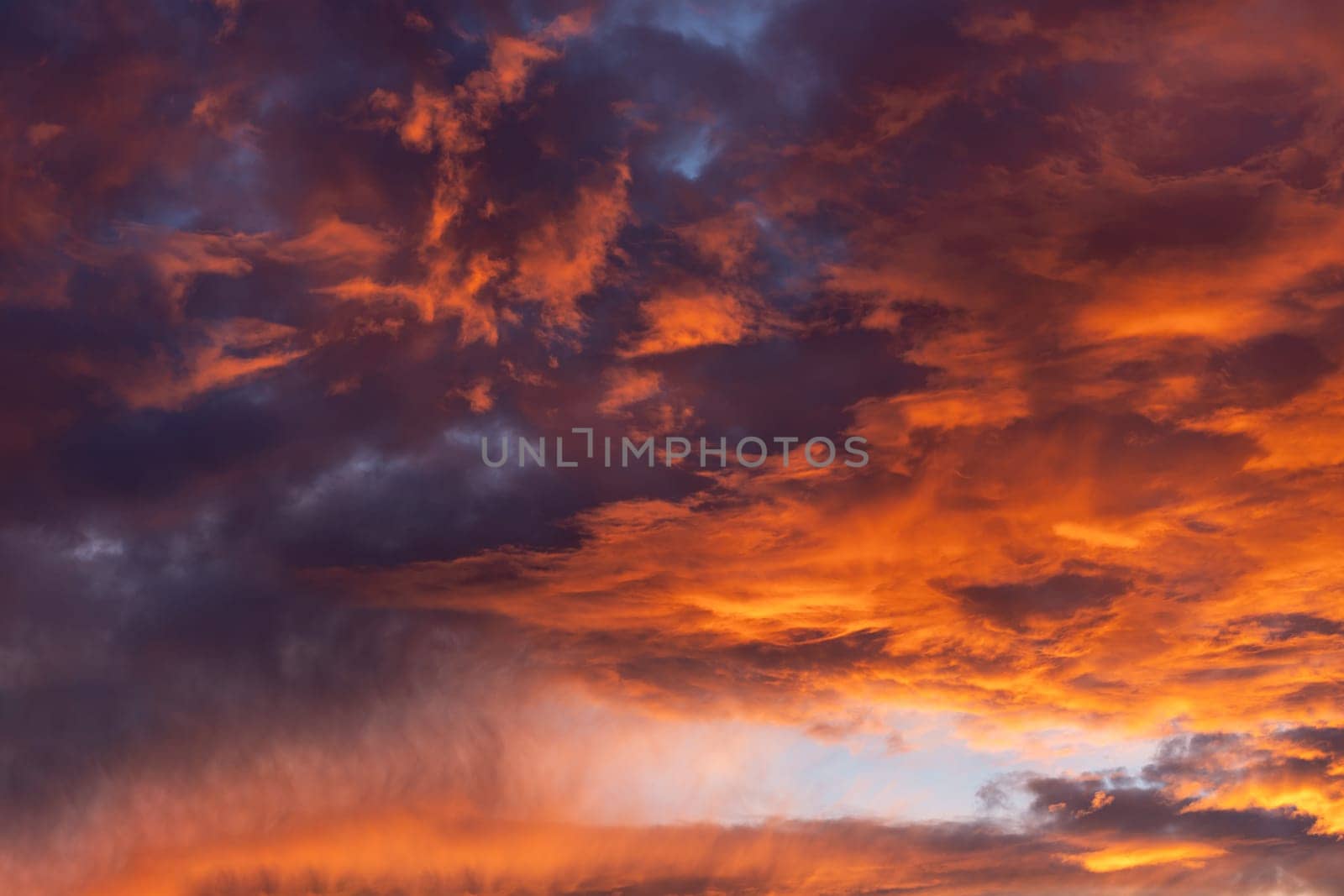 Dramatic fiery cloudy evening sky at sunset, clouds of bright colors in twilight