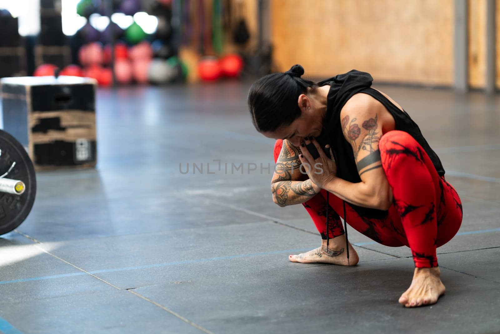 Photo with copy space of a mature sportive woman crouching tired in a gym