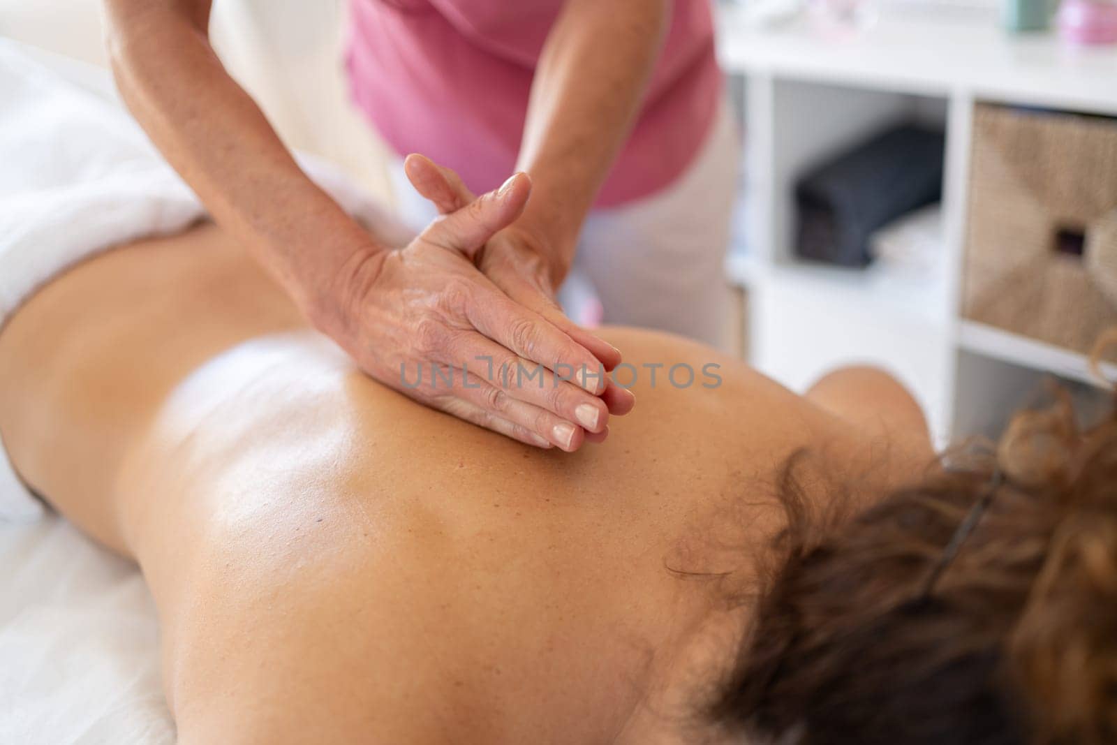 Crop anonymous female osteopath kneading back of patient with special technique during massage session in modern rehabilitation clinic