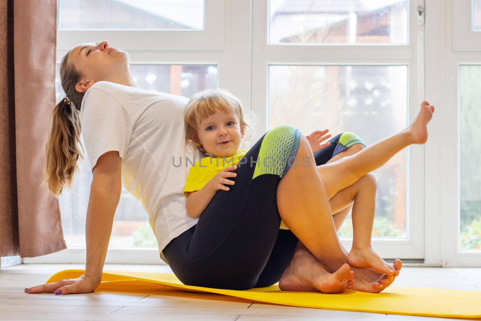 Mother and son family doing fitness, yoga, exercise on a yoga mat at home.