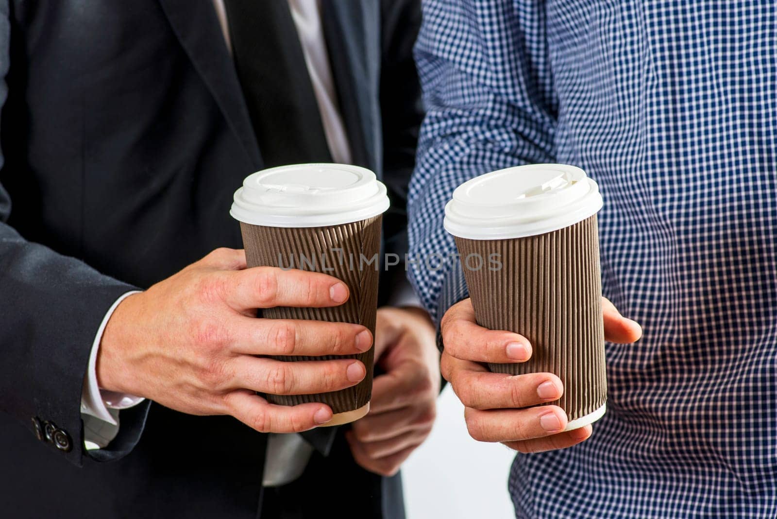 Diverse coworkers with drinks to go in paper cups drinking coffee together, making conversation.