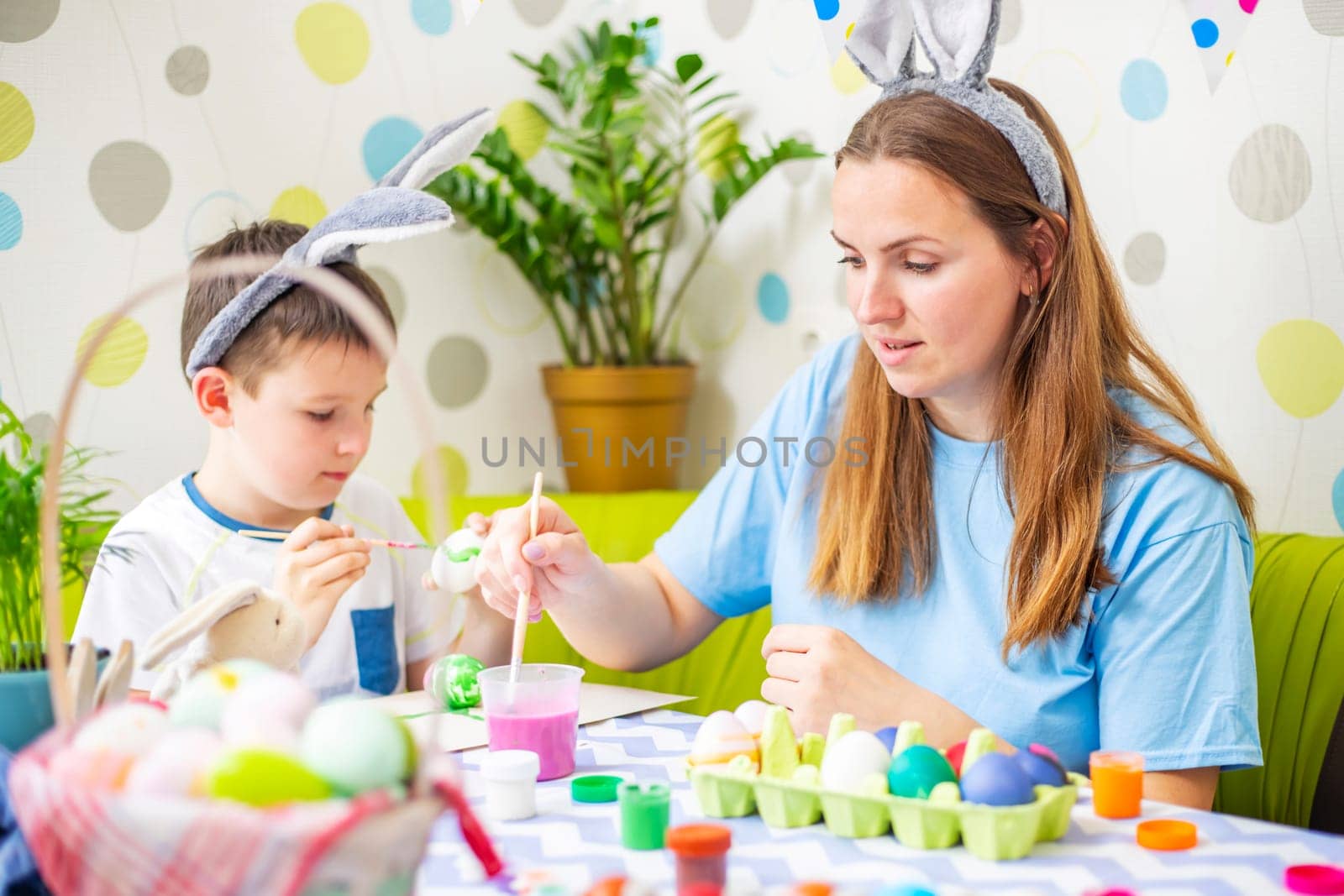 Happy Easter. A mother and her son painting Easter eggs by andreyz