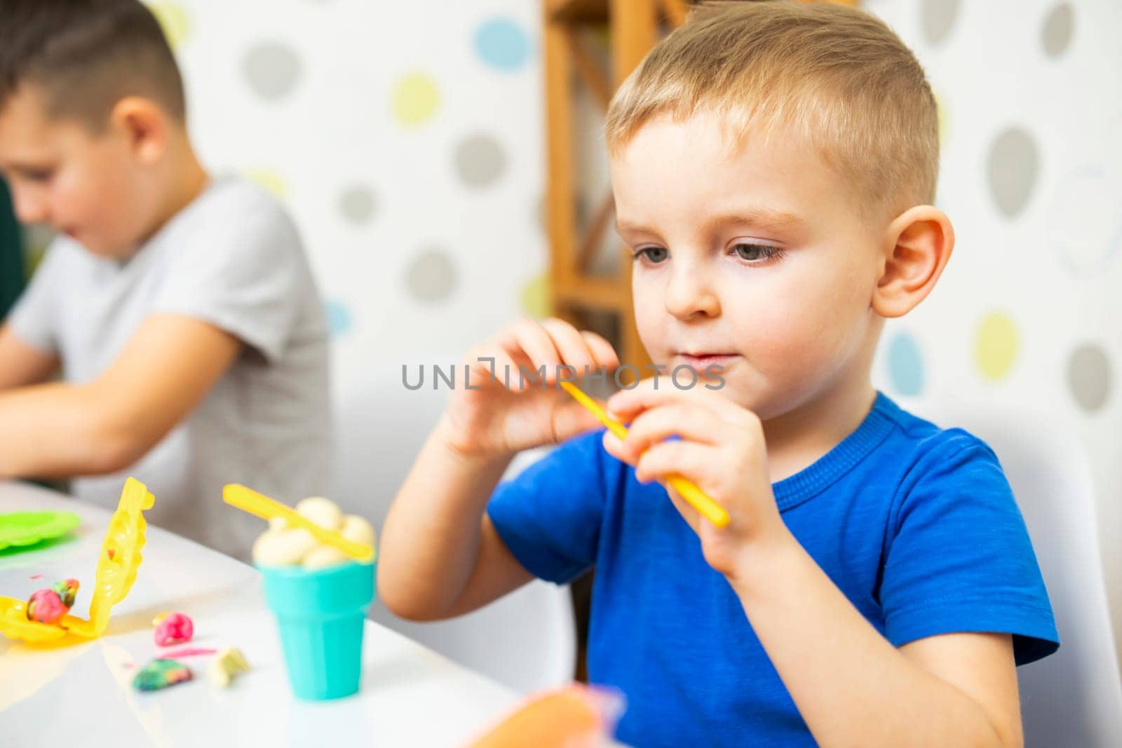 Kids playing with play dough. Cute children sitting at the table and plays with playdough. Creative leisure activity concept