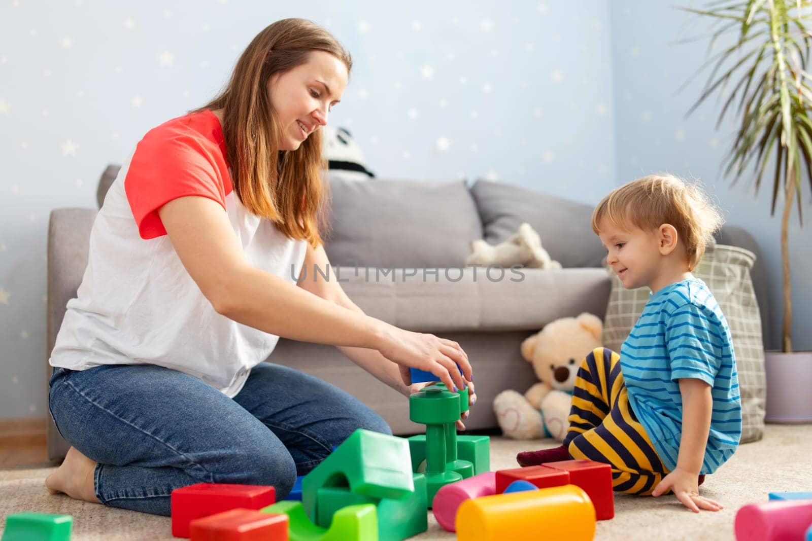Kid and child development specialist playing together with colorful blocks by andreyz