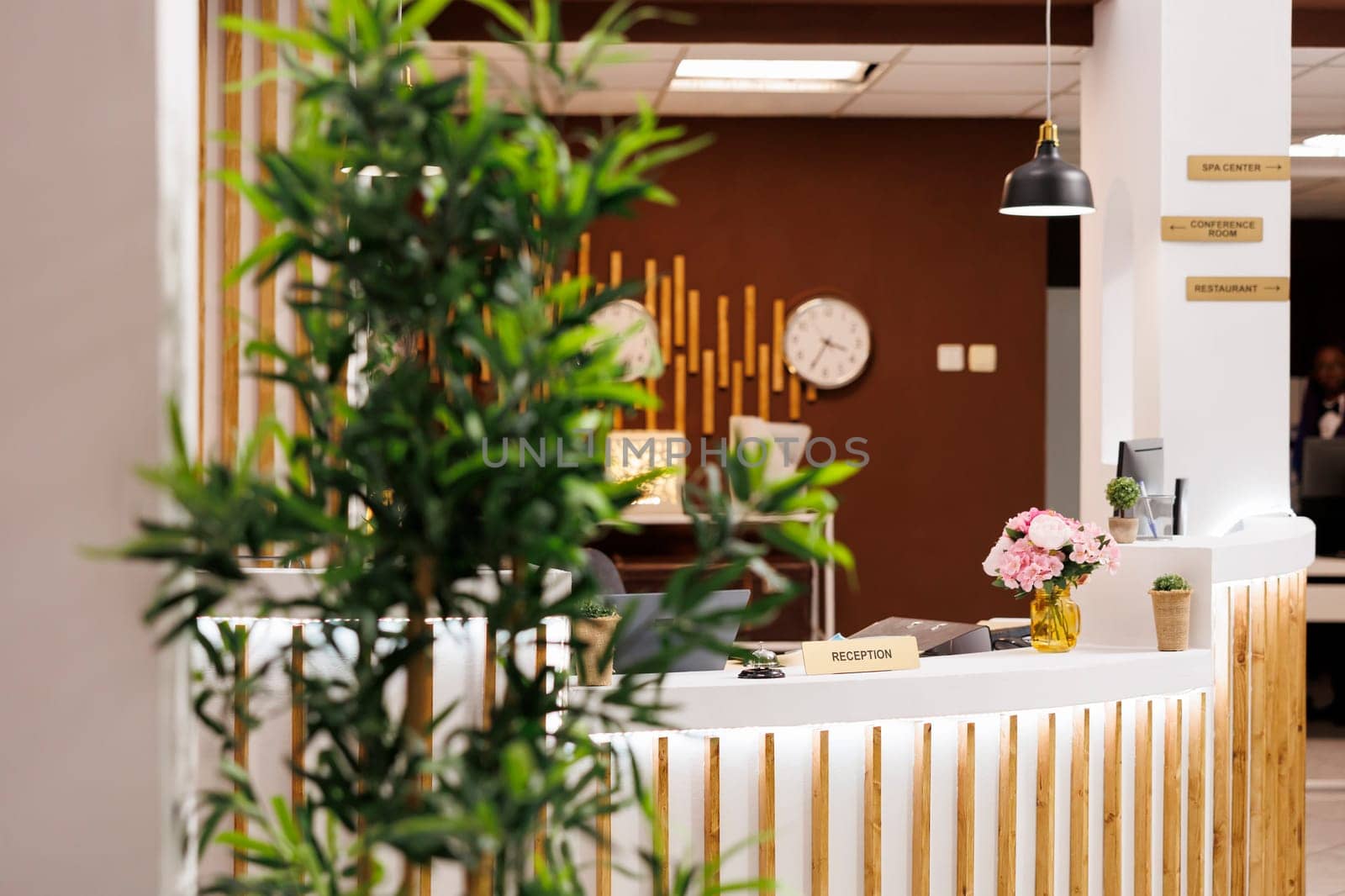 Hotel entrance area, stylish modern reception counter with front desk with row of clocks with different time zones hanging on wall, nobody. Hospitality interior design concept