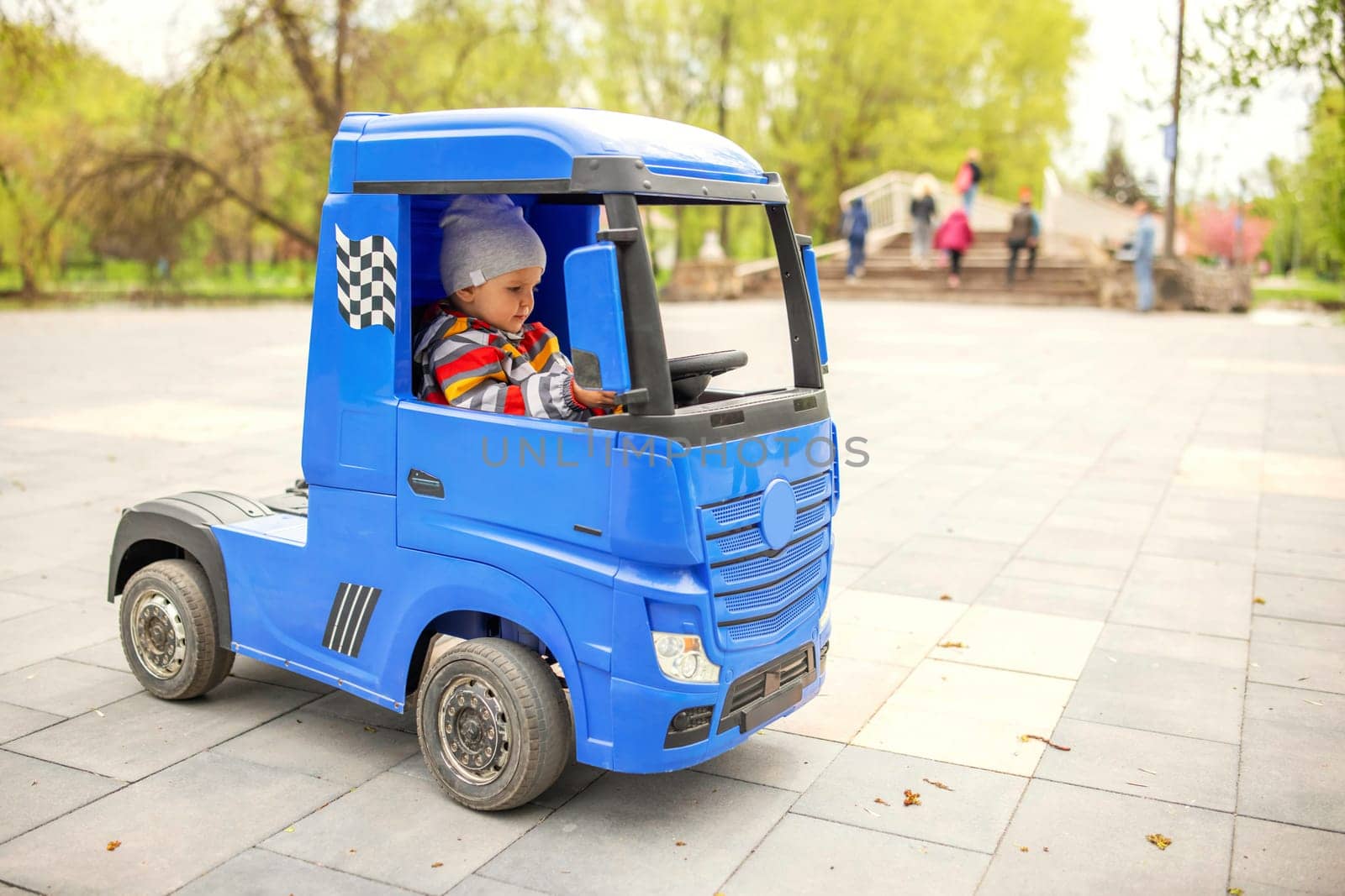 Cute little boy driving electric toy car outdoors in park. by andreyz