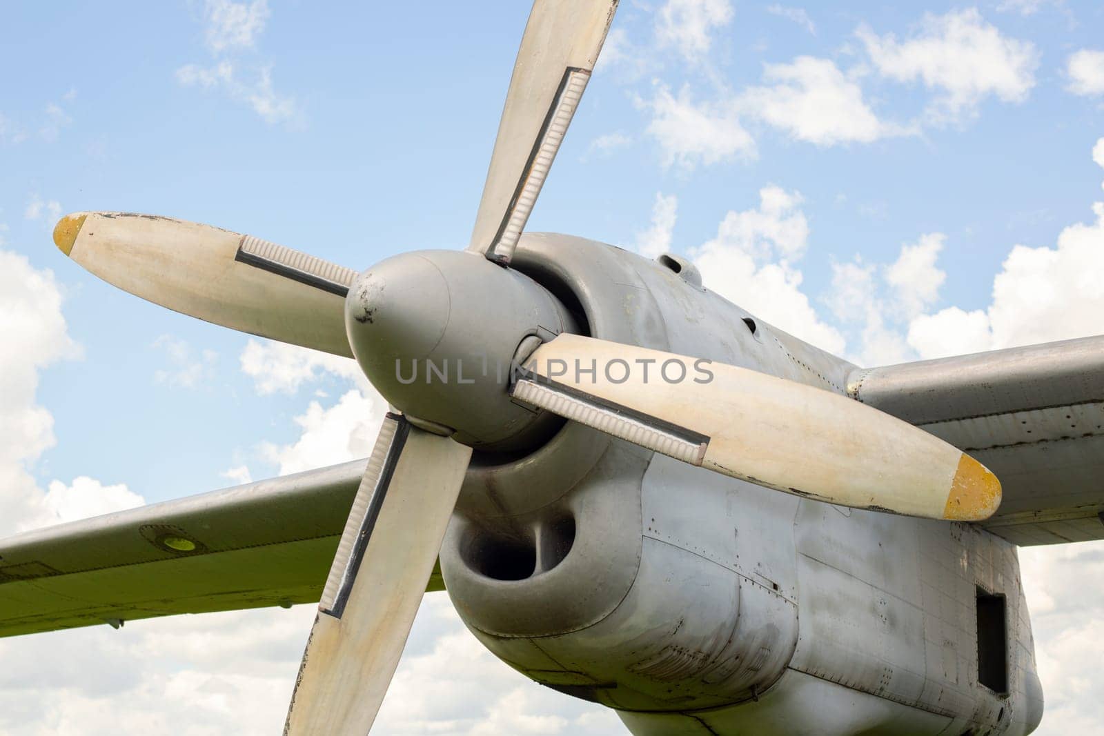 A fragment of airplane wing with four-bladed aircraft propeller against blue sky by andreyz
