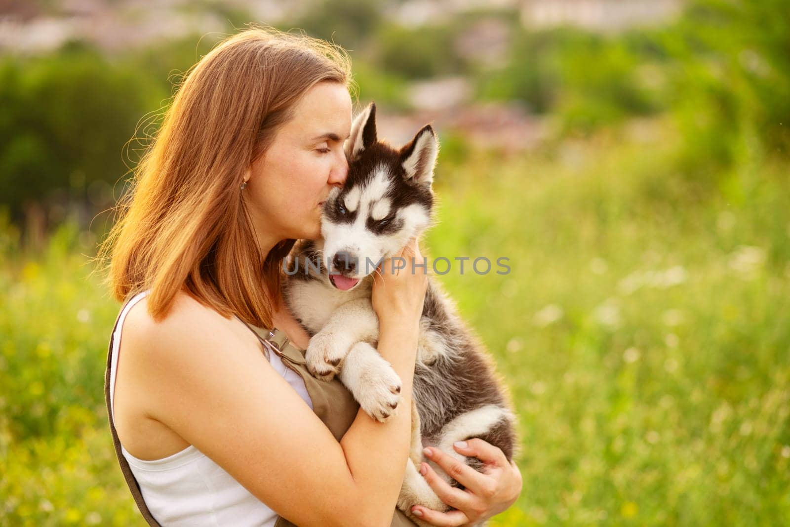 Woman playing with cute little husky puppy dog outdoors. Pet and owner love.