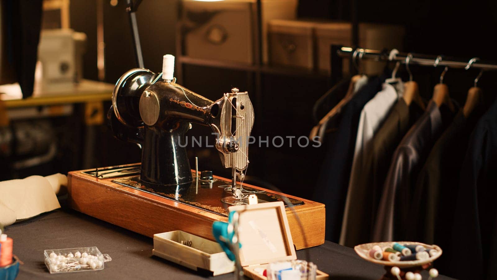 Fashion atelier sewing machine and tools on workshop table, luxury tailoring design and industrial materials. Workstation with fabric and pins for clothes manufacturing process. Close up.