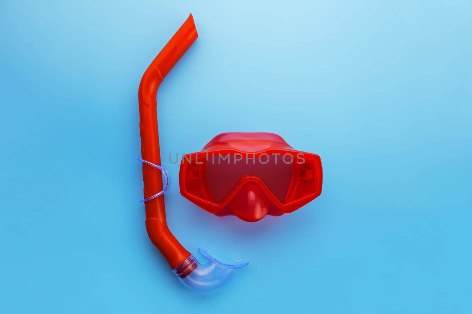 A set of red swimming mask and snorkel on a blue background. Summer, diving, travel, vacation concept