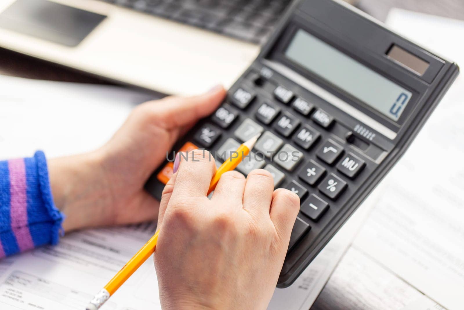 Close up young woman using calculator, managing household monthly budget, summarizing taxes or bills, planning future investments, doing financial affairs at home, accounting bookkeeping concept