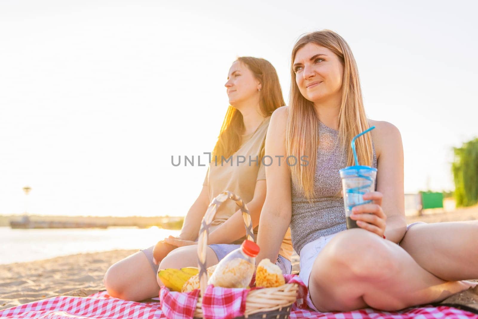 Two young beautiful women are having fun on beach and smiling. Have a carefree time with friends