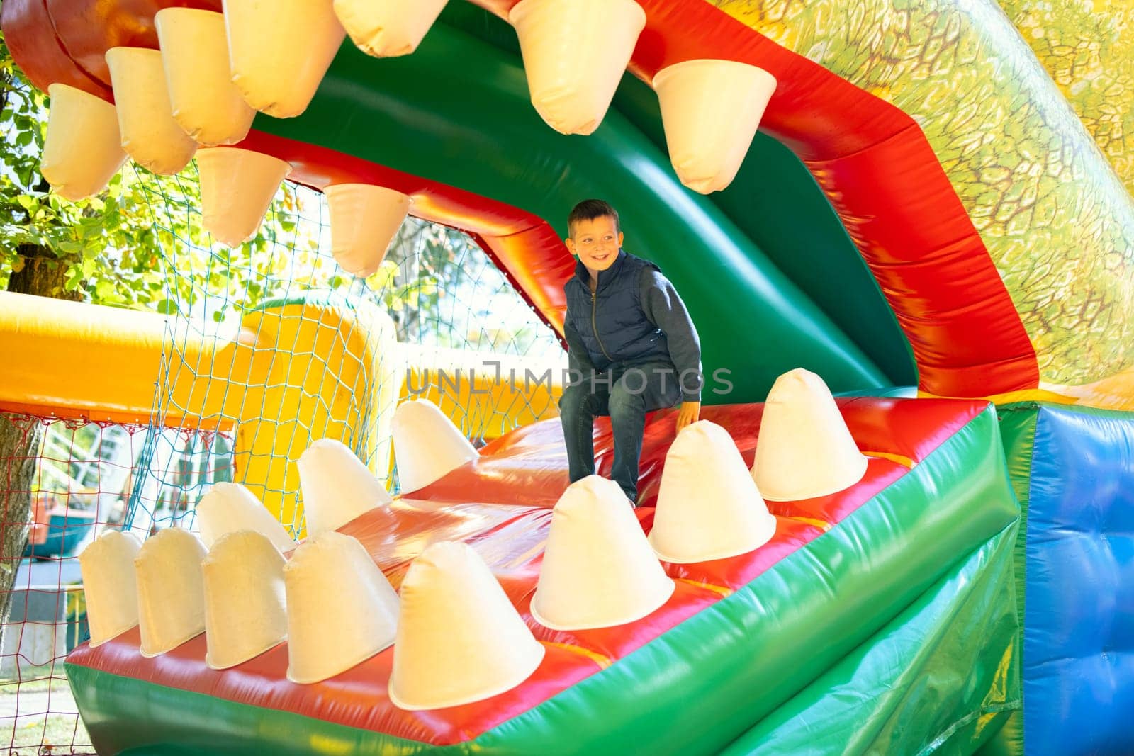Happy boy having a lots of fun on a colorful inflate castle. Colorful playground. Activity and play center for kids.