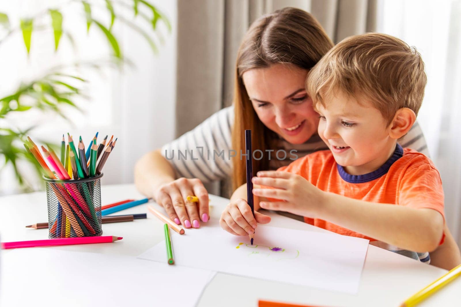 Mother and child drawing with pencils sitting at the desk at home by andreyz