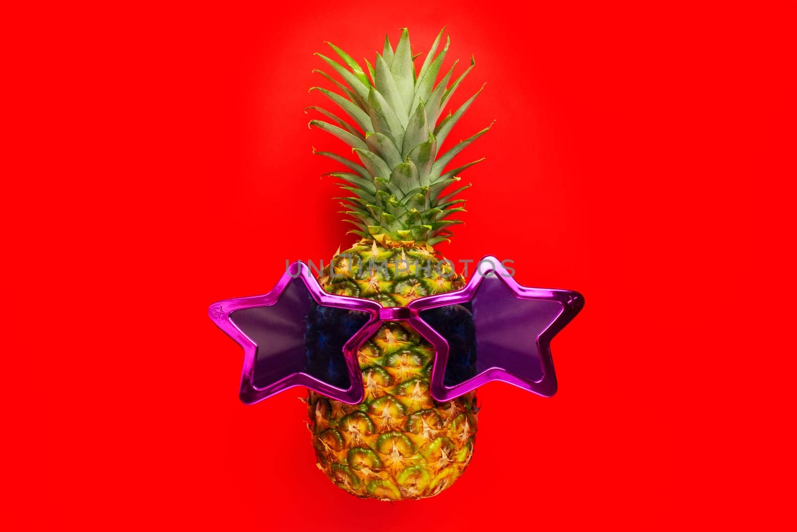 Pineapple with sunglasses on red background. Pineapple in star glasses. by andreyz