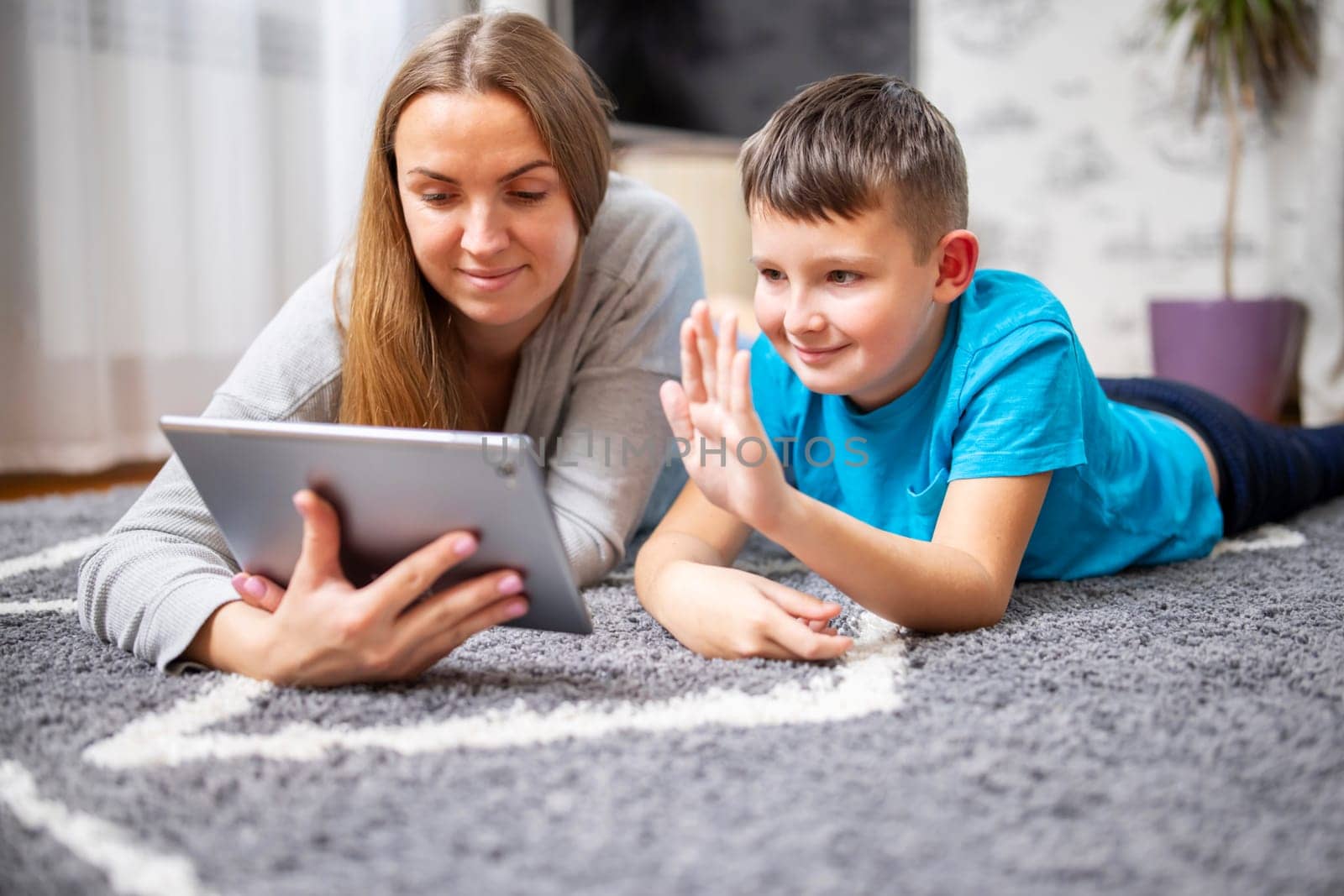 Happy mother and son greeting online looking at web camera using tablet pc by andreyz