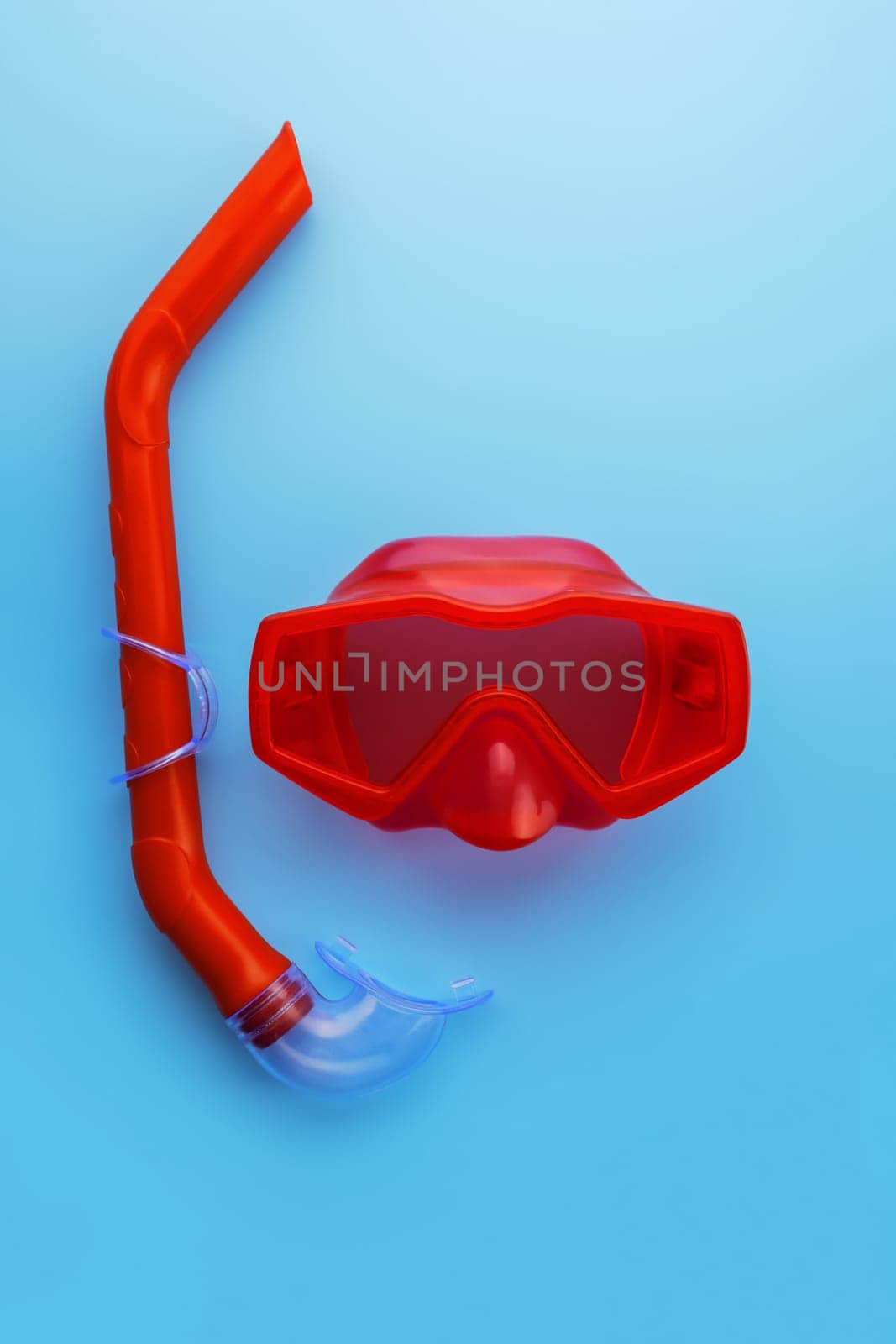 A set of red swimming mask and snorkel on a blue background by andreyz