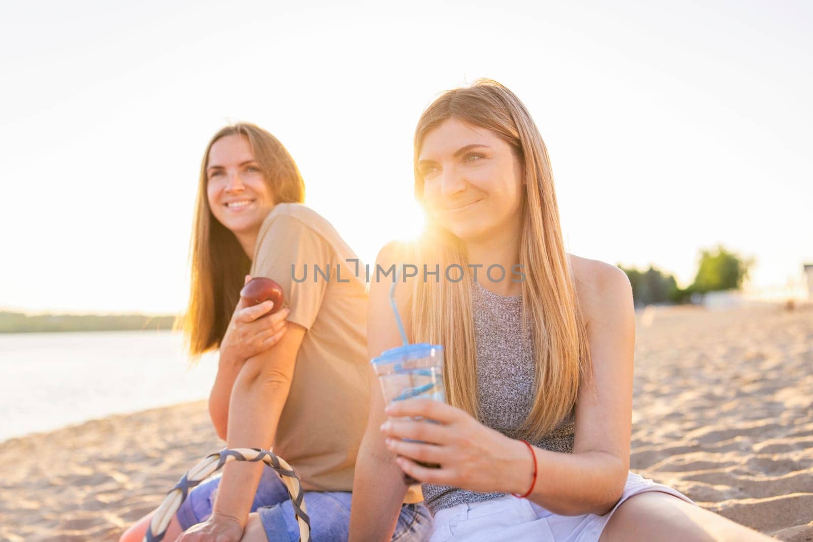 Two young beautiful women are having fun on beach and smiling. Have a carefree time with friends
