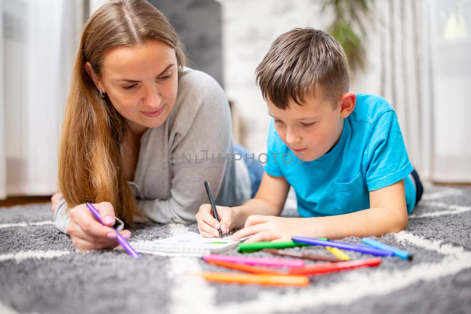 Happy family playing together at home on floor. Mother and her son painting together
