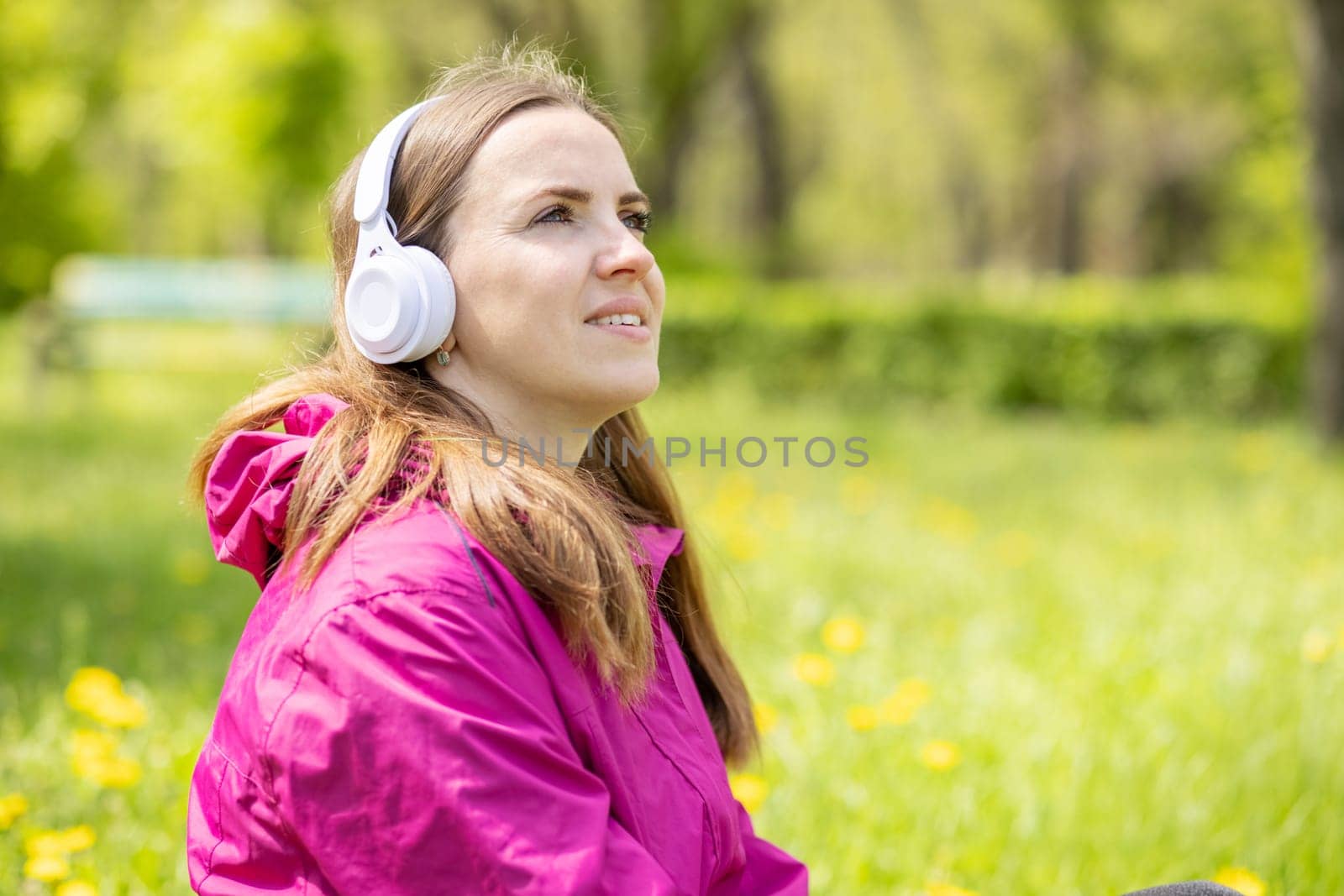Beautiful young woman likes to listen to music with headphones, feeling happy and relaxed in the park