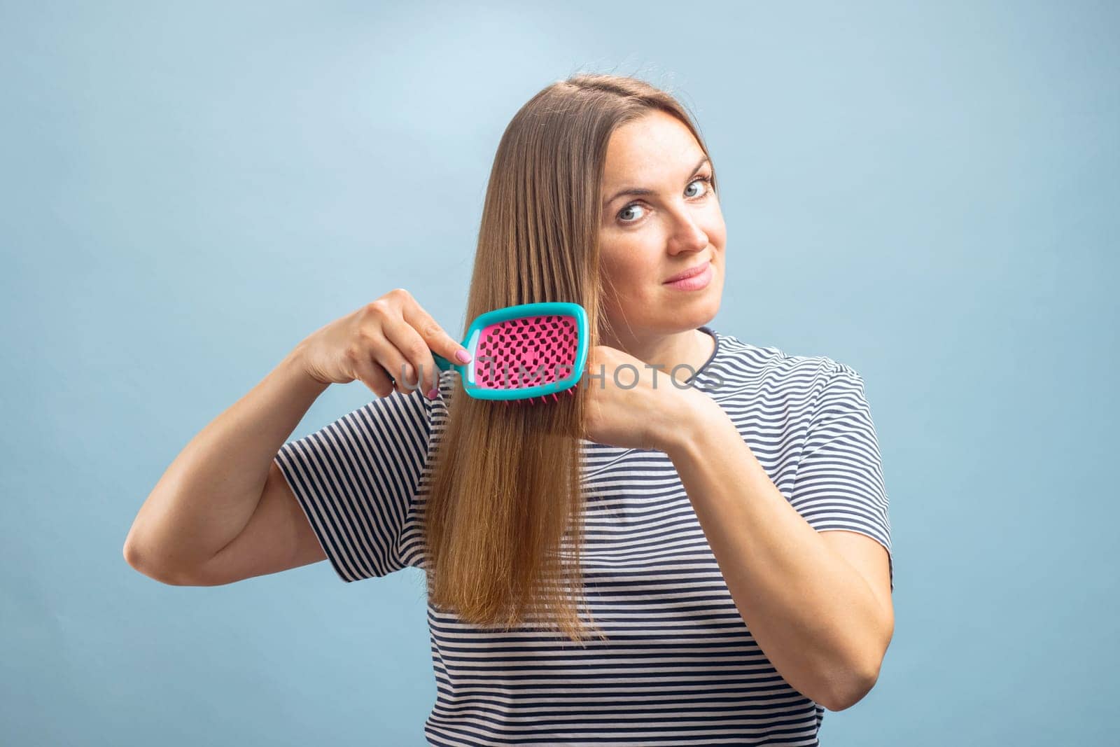 Young beautiful brunette woman brushing her long healthy hair. Haircare concept.