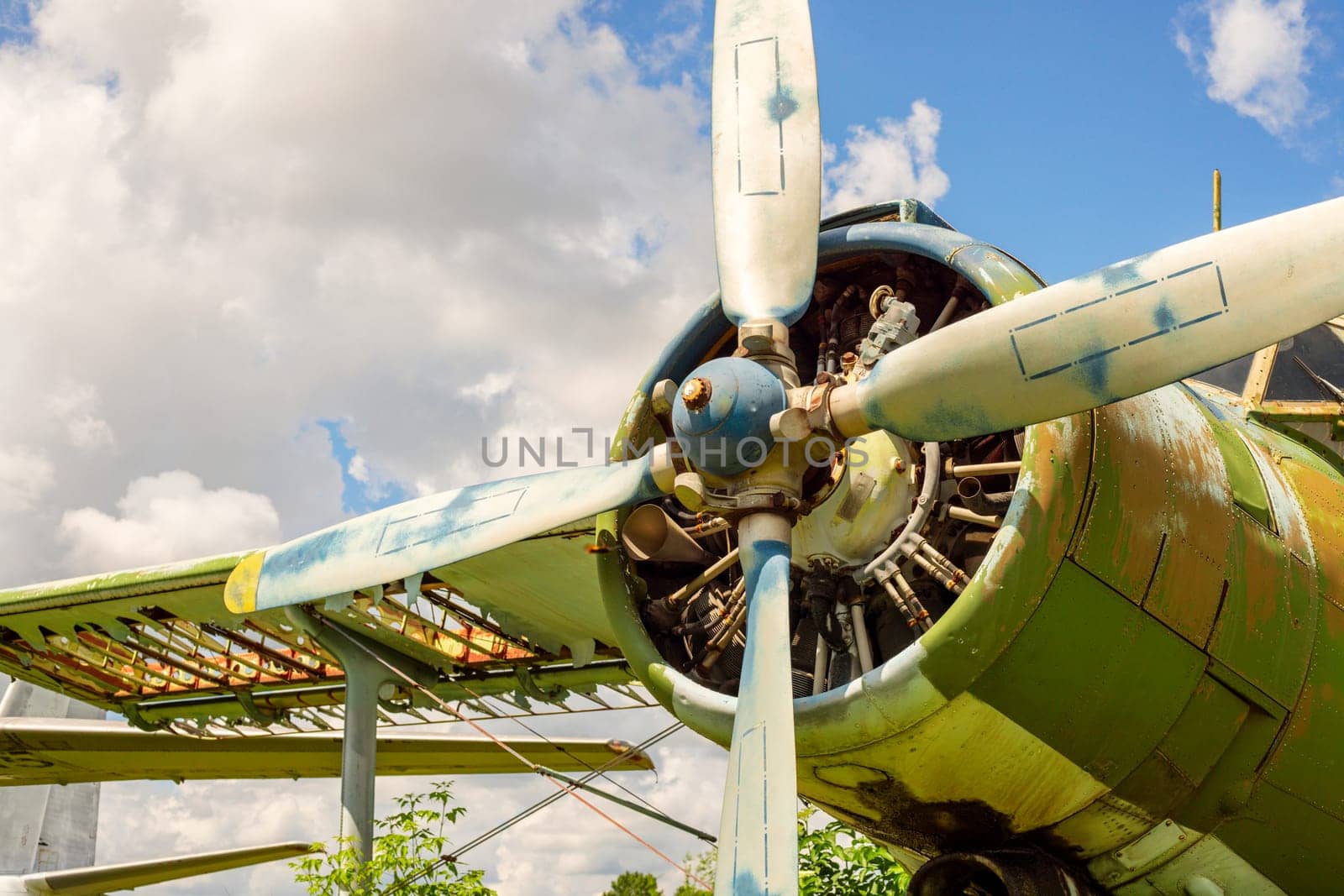 A fragment of an airplane wing with a four-bladed aircraft propeller against blue sky