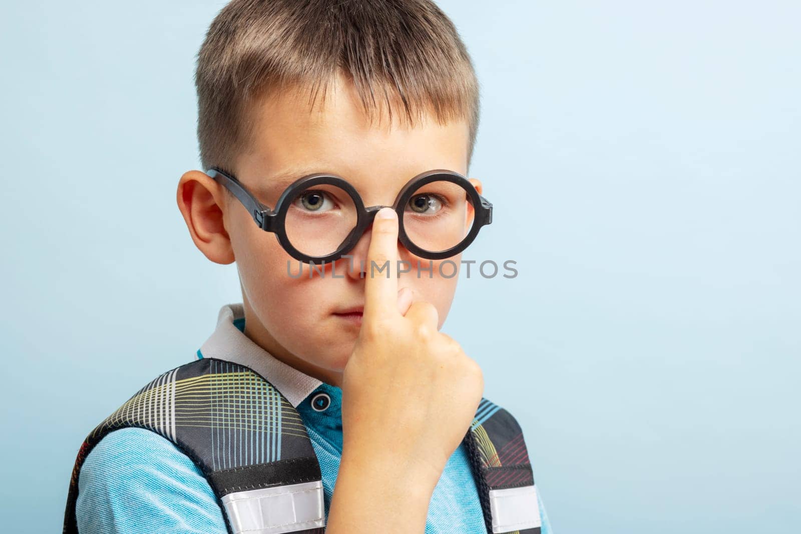 A cute smart school boy in glasses on blue background by andreyz