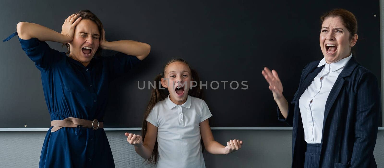 Female teacher, schoolgirl and her mother yell at each other while standing at the blackboard. by mrwed54