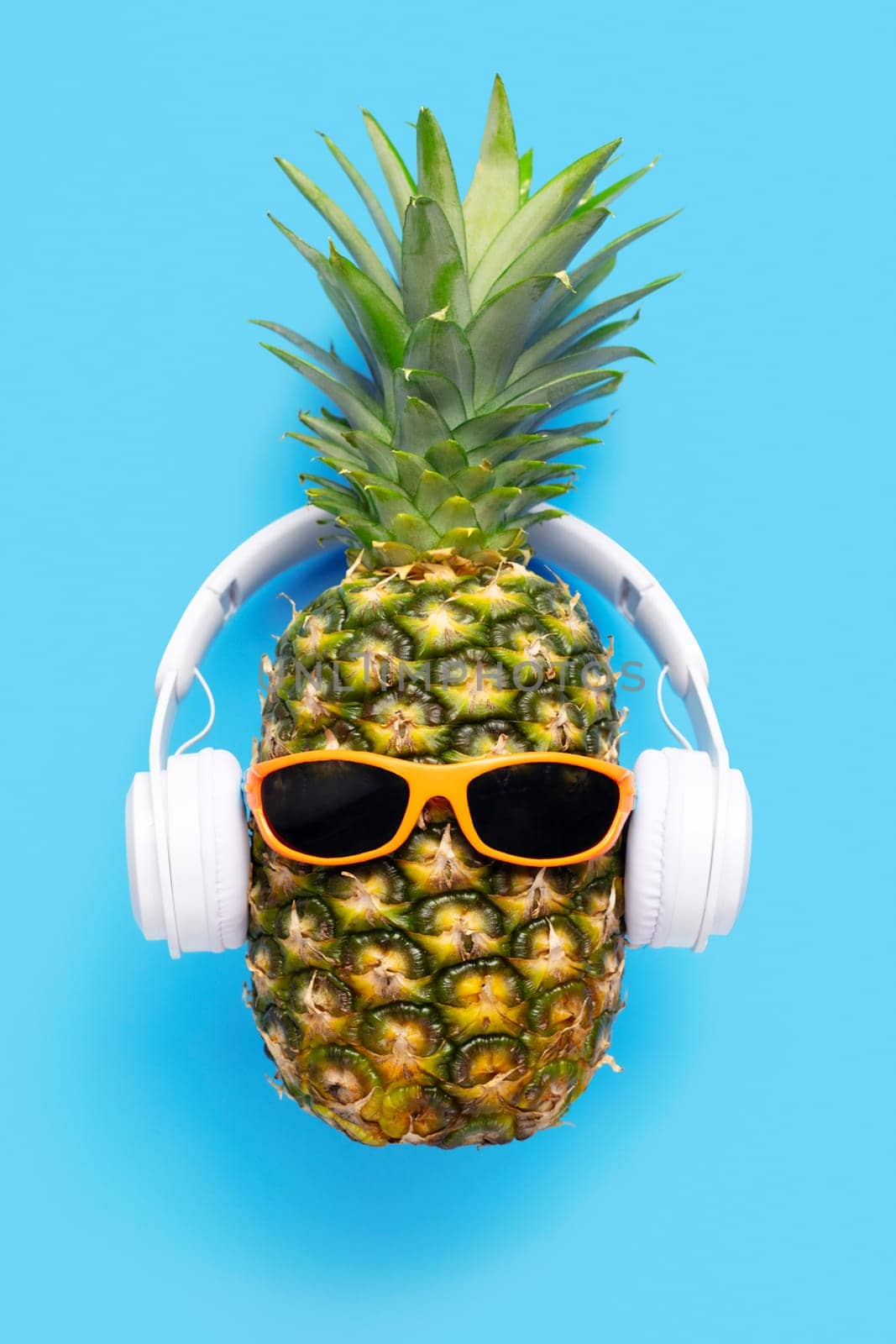 Ripe pineapple with sunglasses and headphones on blue background by andreyz