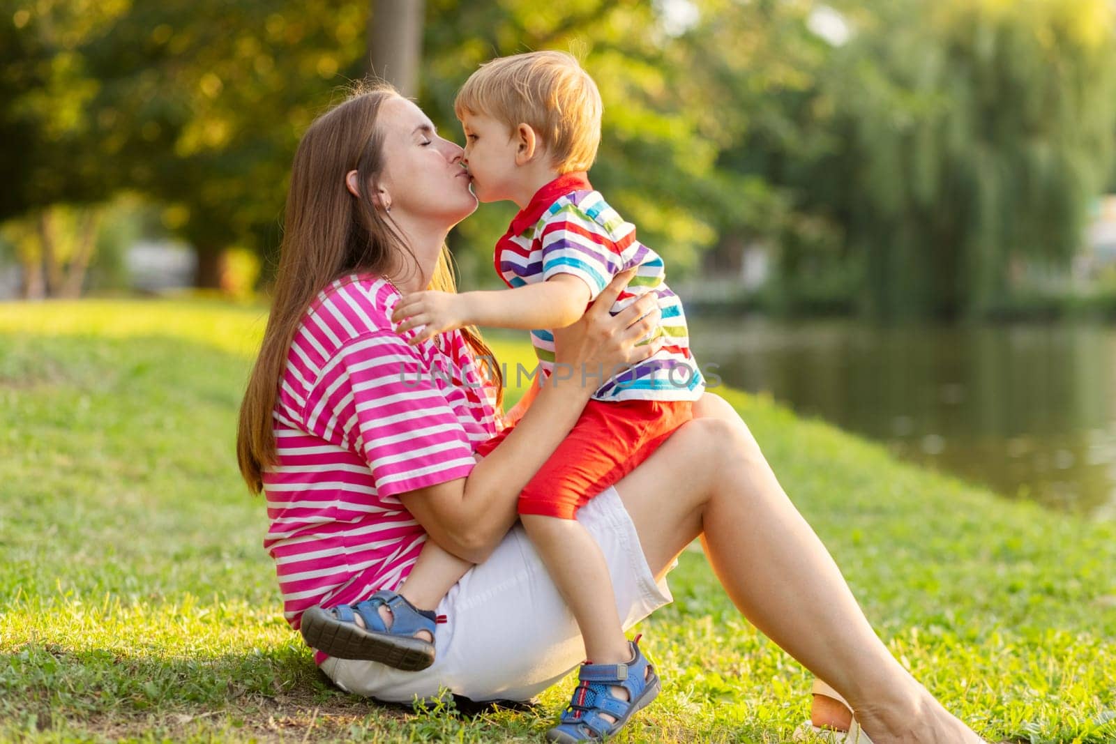 Mother having rest with her little kid son together outdoors in park by andreyz